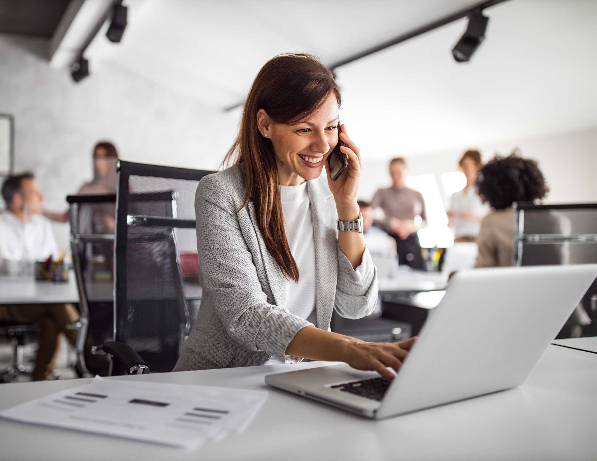 CIO/CTO on a call working on a laptop in an open office